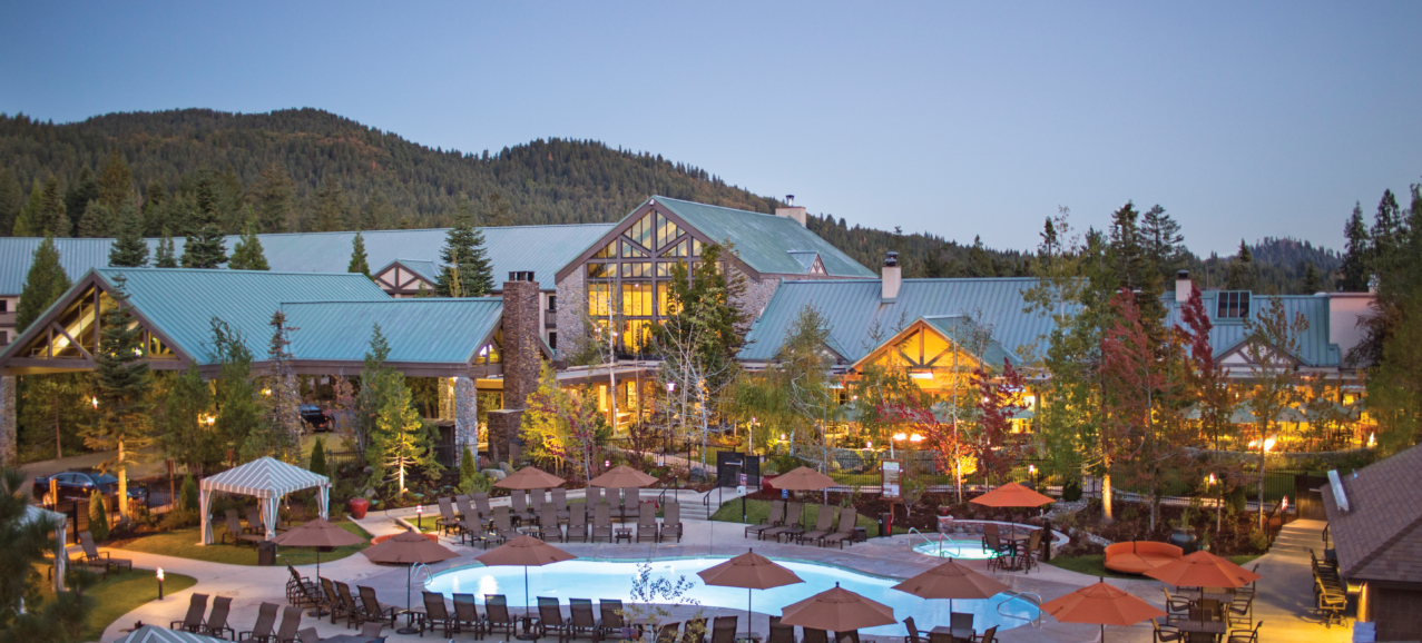 The Tenaya resort with a pool surrounded by umbrellas at dusk.